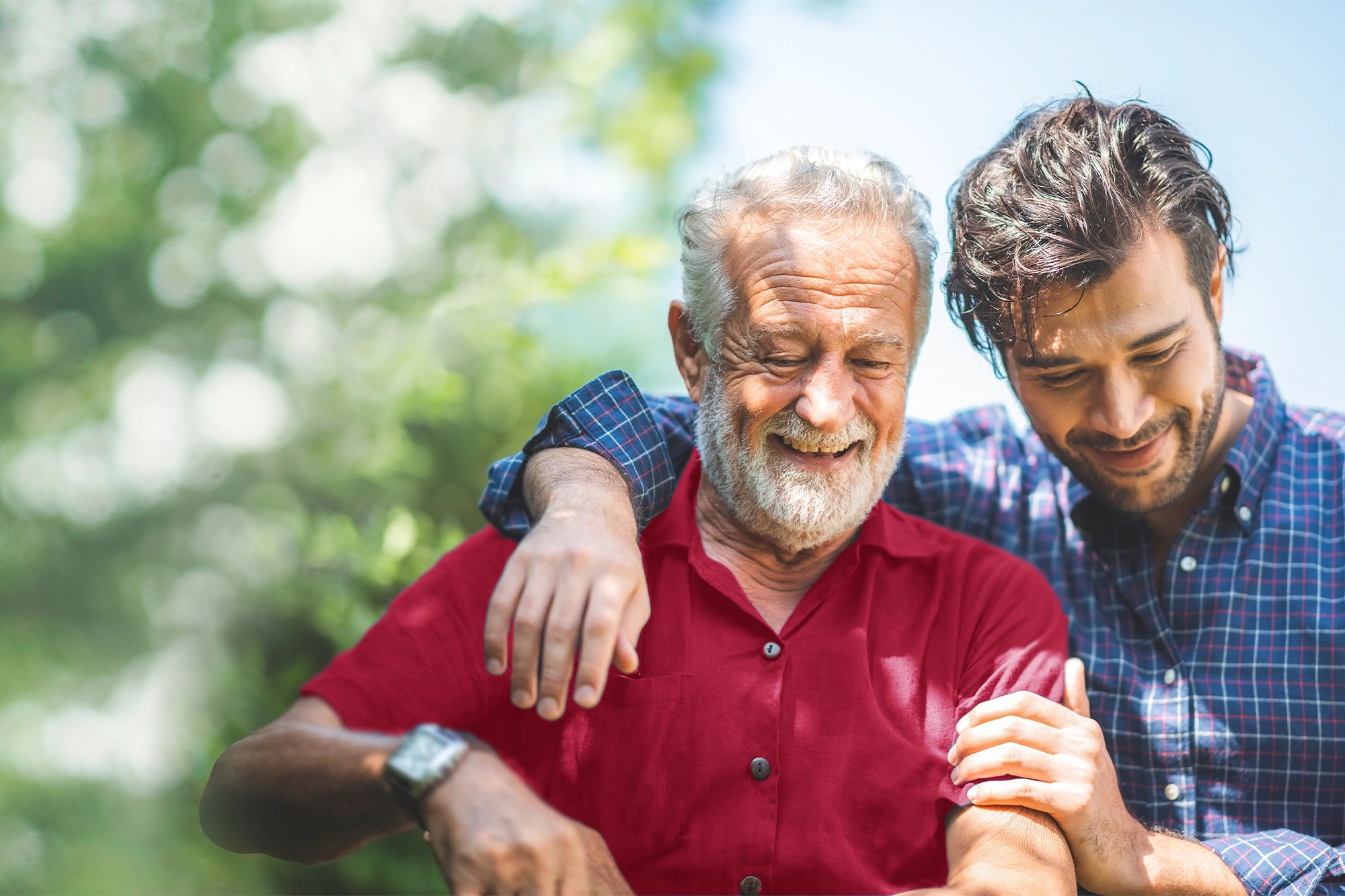Two men smiling, the young man has his arm around the older man's shoulders
